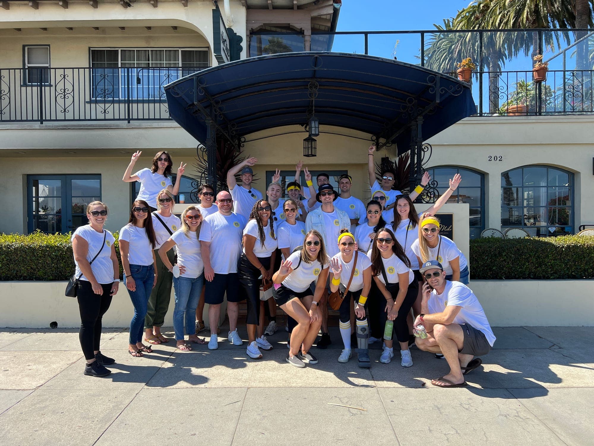 The revenue team in matching white T-shirts and yellow headbands outside a Spanish-style building.
